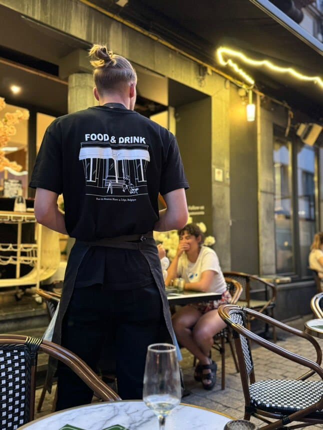 T-shirt noir imprimé au dos « Food & Drink » porté par le personnel d'un restaurant
